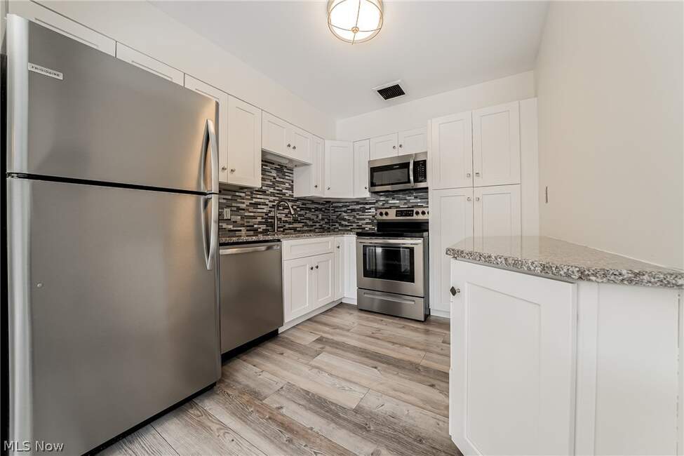 Unit 413 kitchen with white cabinets, stainless refrigerator and range