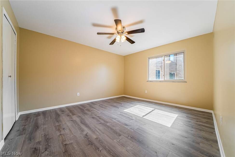 Unfurnished bedroom with window, ceiling fan and wood-look floor at Unit 413